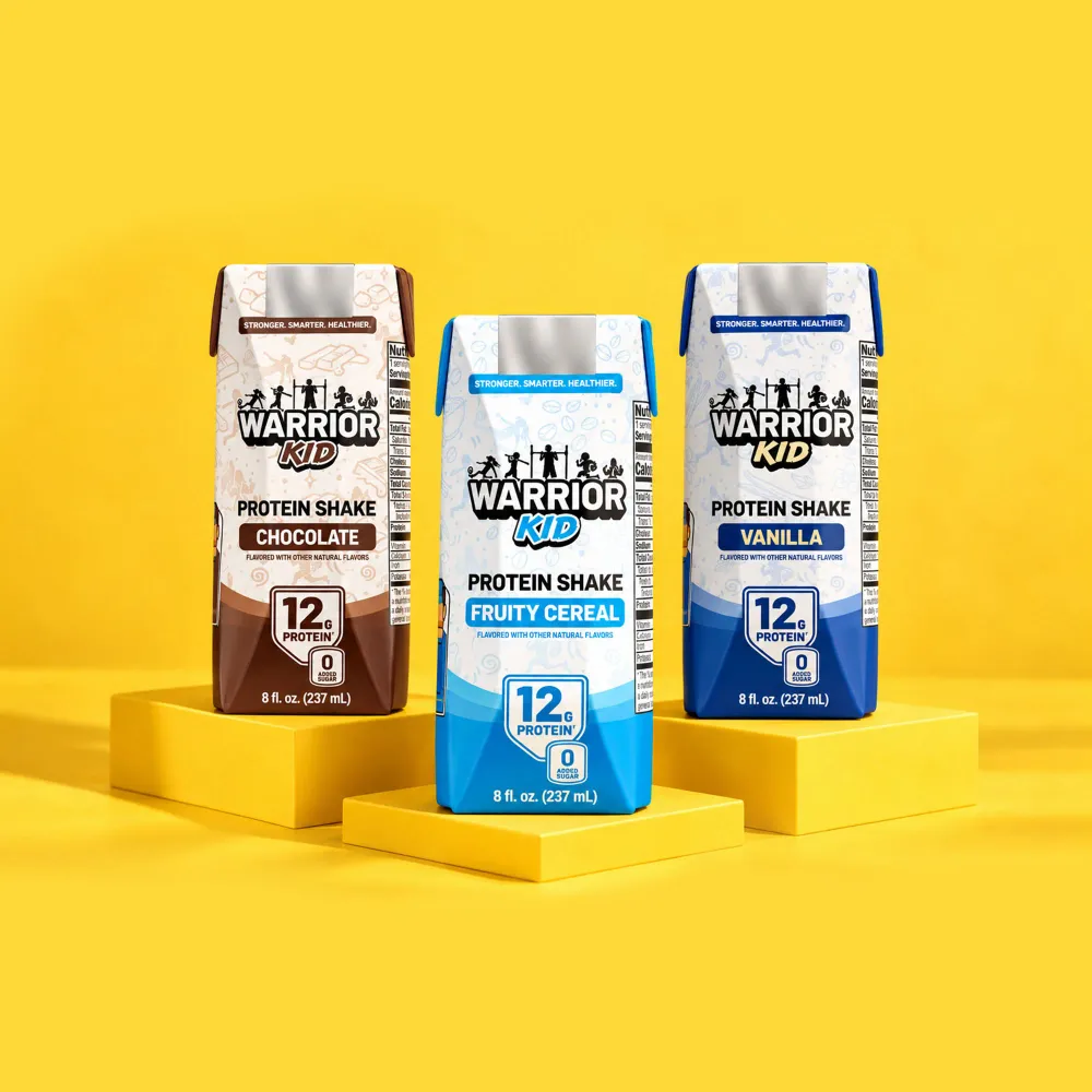 Warrior Kid Protein Shake cartons in Chocolate, Fruity Cereal and Vanilla on yellow platforms
