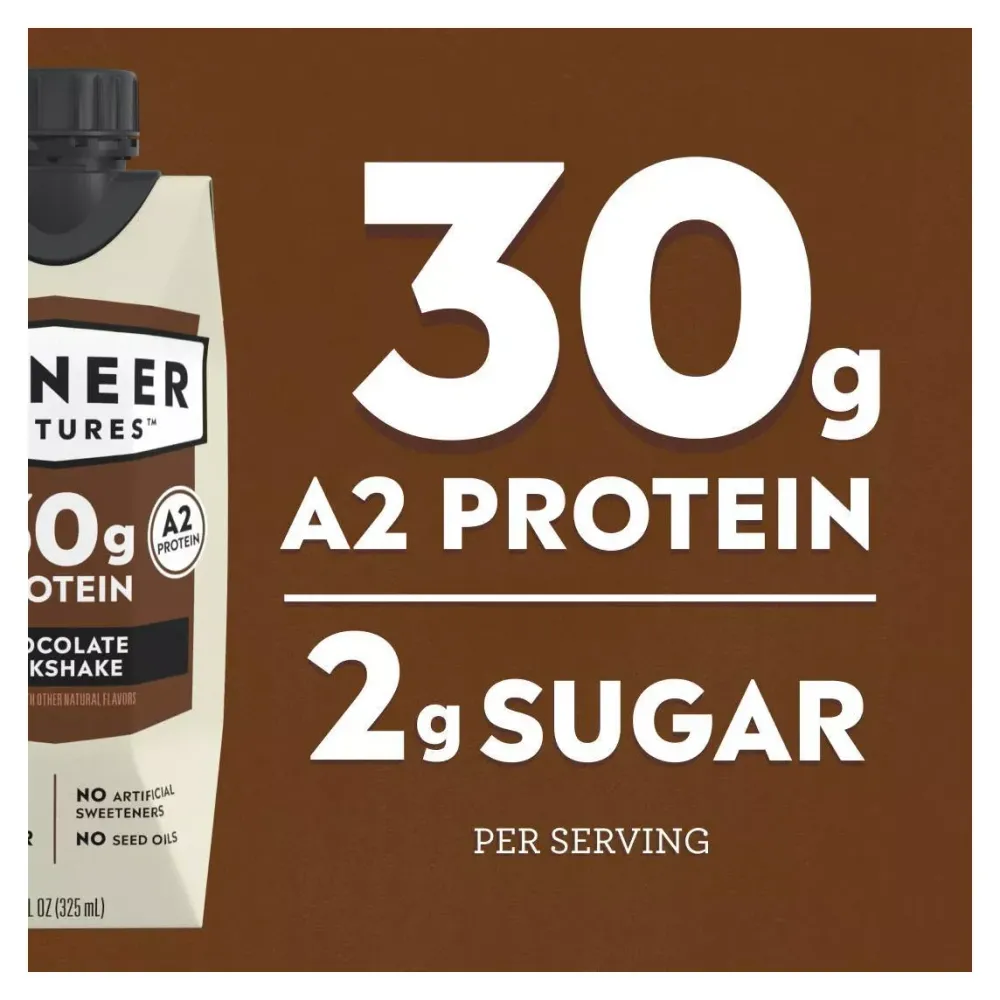 A brown promotional graphic shows large white text reading “30g A2 Protein” and “2g Sugar” per serving beside a partially cropped carton of Pioneer Pastures chocolate milkshake