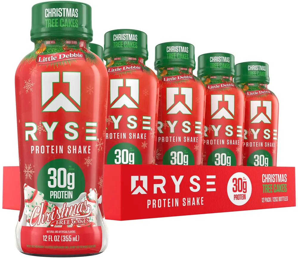 A 12-pack of RYSE Protein Shake RTD Little Debbie Christmas Tree Cakes bottles in a red holiday tray, with one bottle in front