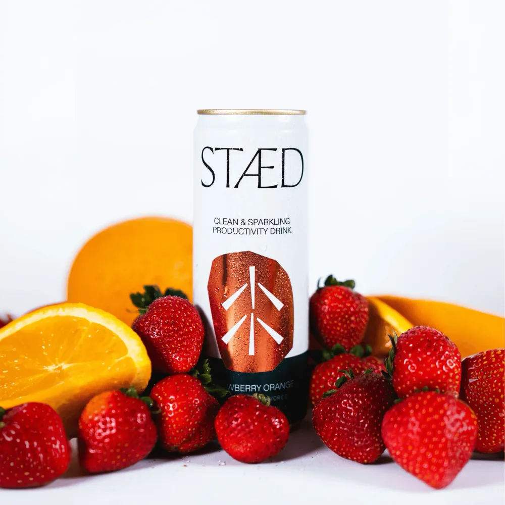 A white Staed Clean & Sparkling Productivity Drink can stands among strawberries and orange slices